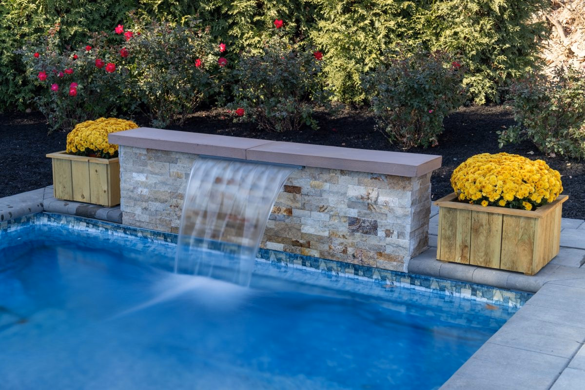 A beautiful modern formal waterfall kit flowing into a swimming pool