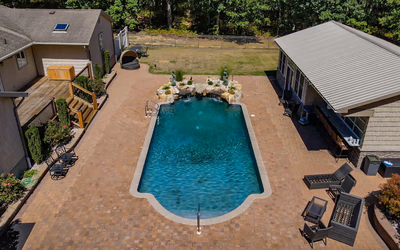 Multi-tiered natural stone boulder waterfalls cascading into a pool surrounded by small green plants