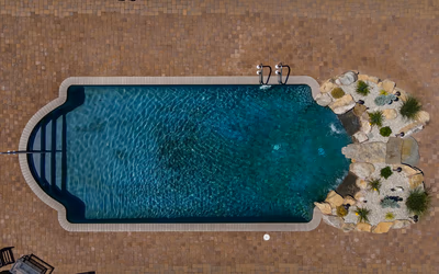 Two-tiered natural stone boulder waterfalls cascading into a pool with surrounding small garden plants