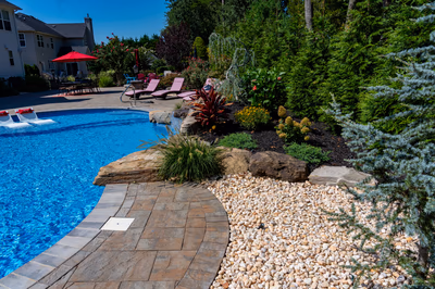 Multi-tiered natural stone boulder waterfall cascading into a pool surrounded by lush greenery