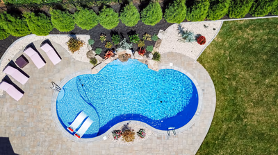 Multi-tiered natural stone boulder waterfall cascading into a freeform pool with lush landscaping