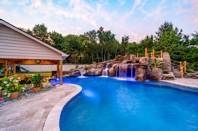 Multi-tiered natural stone boulder waterfalls cascading into a blue pool surrounded by lush greenery