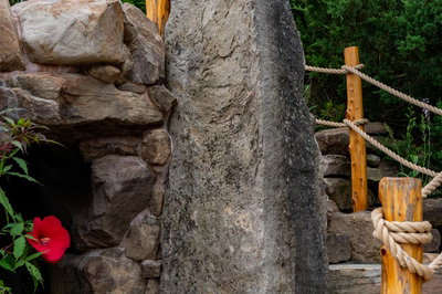Multi-tiered natural stone boulder waterfall cascading into a pool surrounded by lush tropical plants