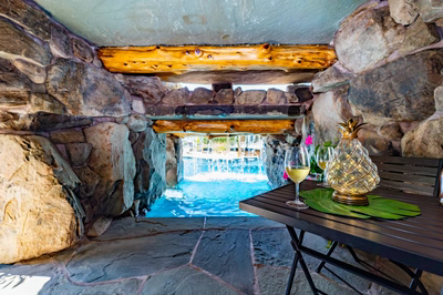Multi-tiered natural stone boulder waterfall cascading into a pool with lush tropical landscaping