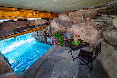 Multi-tiered natural stone boulder waterfall cascading into a pool beside vibrant pink flowering plants