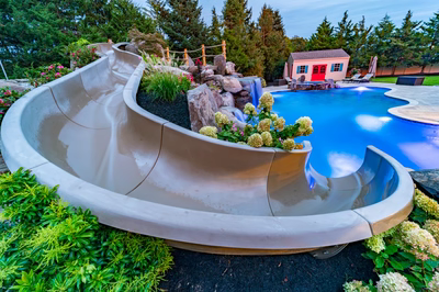 Multi-tiered natural stone boulder waterfall cascading into a freeform pool with lush garden landscaping