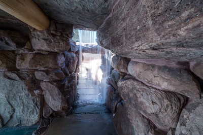 Multi-tiered natural stone boulder waterfall with curtain flow cascading into a custom grotto pool