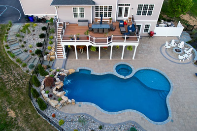 Two-tiered natural stone boulder waterfall cascading into a freeform pool with surrounding garden plants
