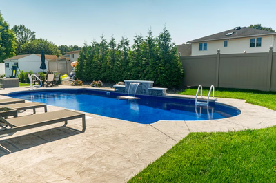 Multi-tiered natural stone boulder waterfall cascading into a blue pool surrounded by evergreen shrubs