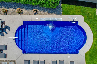 Single-tier natural stone boulder waterfall cascading into a blue pool surrounded by green landscaping