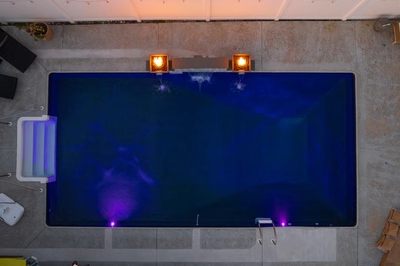 Single-tier natural stone boulder waterfall flowing into a rectangular pool with glowing fire features