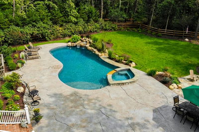 Multi-tiered natural stone boulder waterfall cascading into a freeform pool with lush greenery
