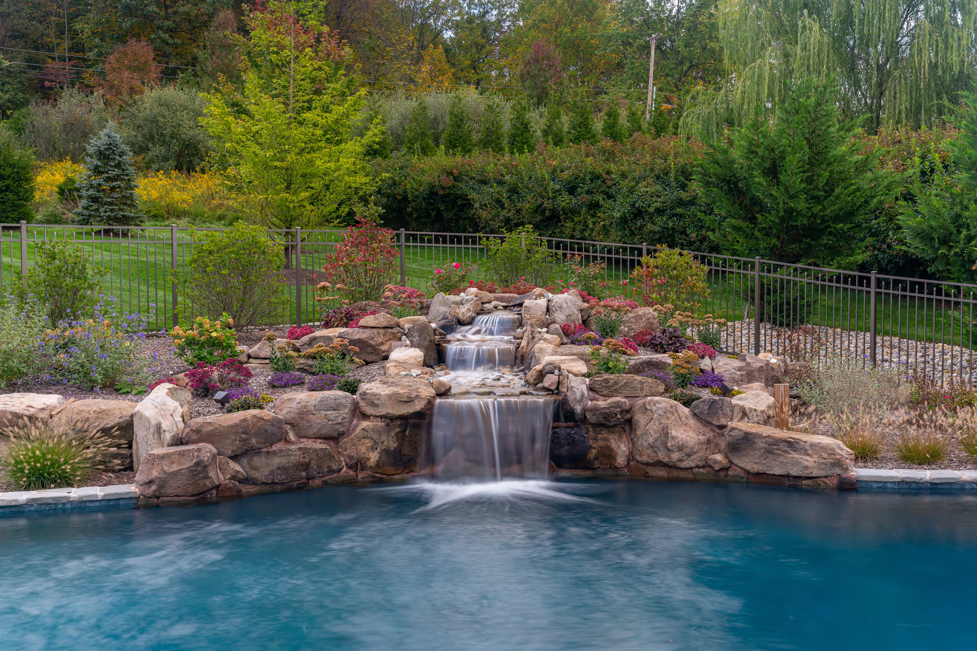 Multi-tier natural-stone waterfall cascading over stacked stone shelves into a pool