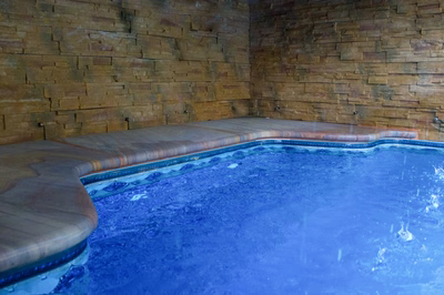 Single-tier stacked stone wall scuppers cascading into a vibrant blue freeform pool