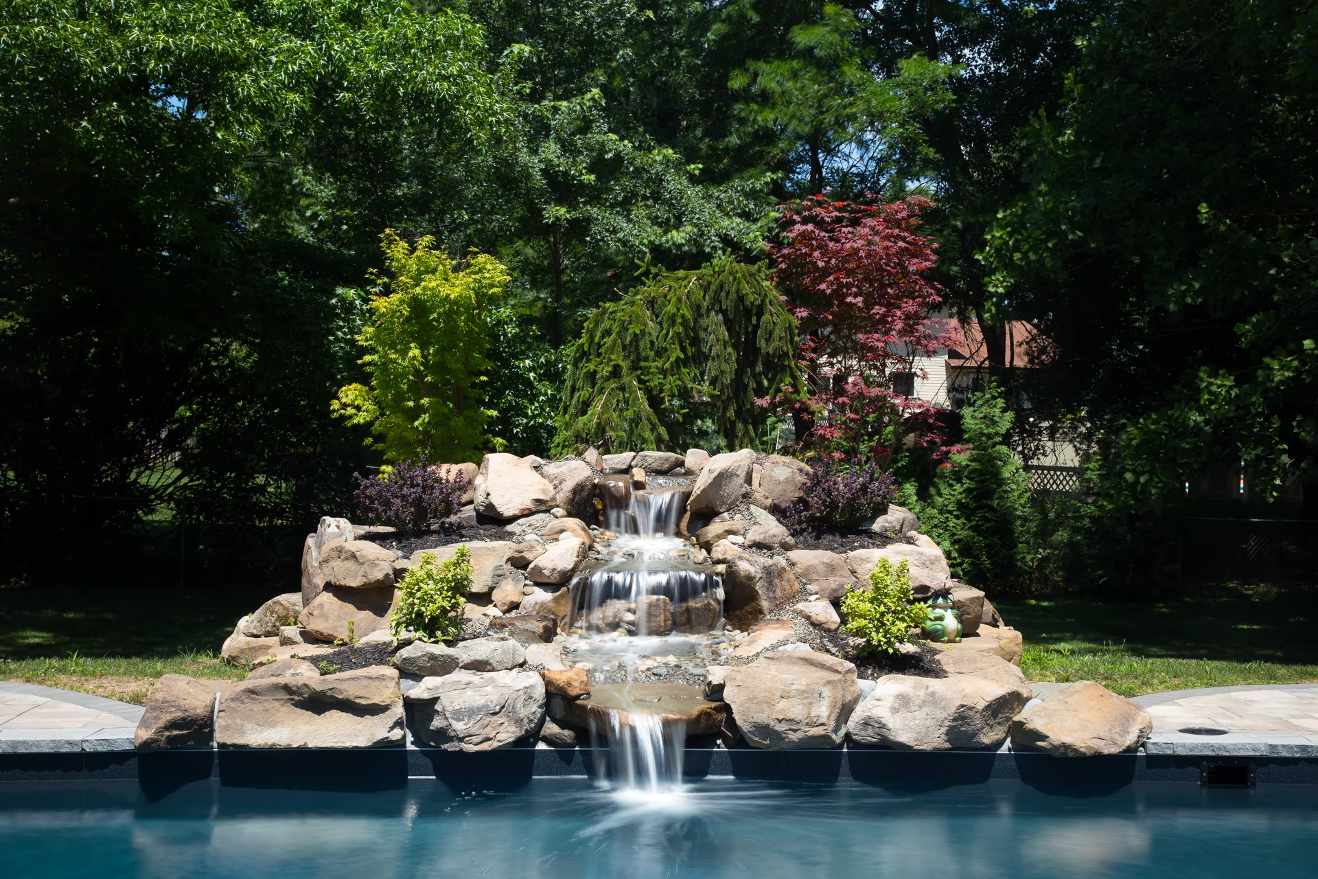 Three-tier stone waterfall stepping down stacked shelves into a pool