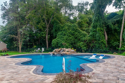 Natural stone boulder waterfall cascading over multiple tiers into a freeform pool with lush greenery