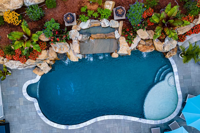 Multi-tiered natural stone boulder waterfall cascading into a freeform pool with lush tropical landscaping