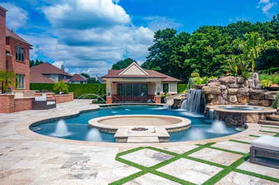 Multi-tiered natural stone boulder waterfall cascading into a custom pool with lush tropical landscaping
