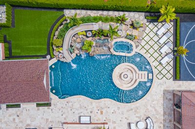 Multi-tiered natural stone boulder waterfall cascading into a freeform pool with lush tropical landscaping