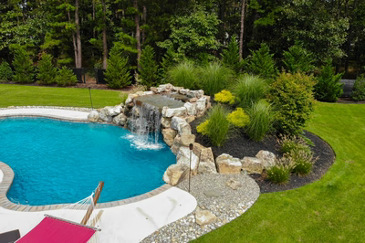 Two-tiered boulder waterfall cascading into a freeform pool surrounded by lush garden landscaping