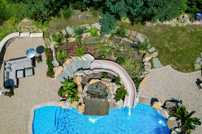 Double-tiered natural stone boulder waterfall cascading into a pool surrounded by lush tropical landscaping