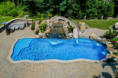 Multi-tiered natural stone boulder waterfall cascading into a pool surrounded by lush tropical landscaping