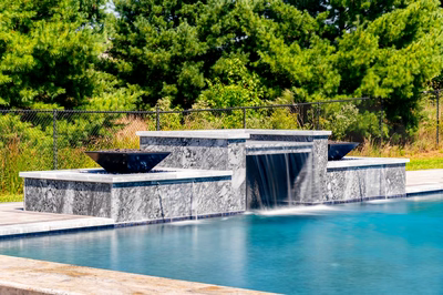 Multi-tiered natural stone waterfall with sheer descents into a pool surrounded by lush greenery