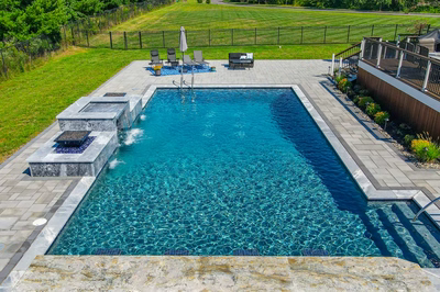 Modern two-tiered stone water feature with sheer descents flowing into a rectangular pool