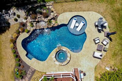 Multi-tiered natural stone boulder waterfall cascading into a freeform pool with lush garden plants