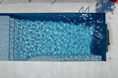 Single-tier natural stone boulder waterfall cascading into a rectangular pool with concrete surrounds