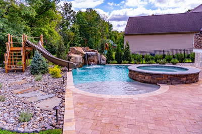 Single-tier natural stone boulder waterfall with sheet flow cascading into a pool near trees