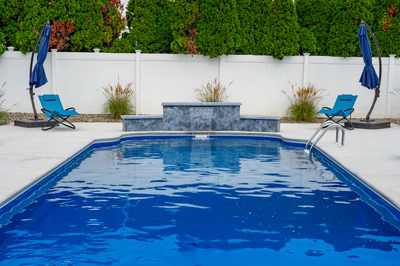 Multi-tiered natural stone waterfall cascading into a pool with surrounding ornamental grasses and lush greenery
