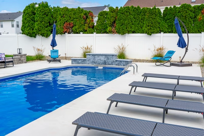 Three-tiered natural stone boulder waterfall cascading into a pool with surrounding ornamental grasses