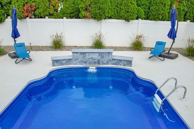 Three-tiered natural stone waterfall cascading into a blue pool surrounded by lush green hedges