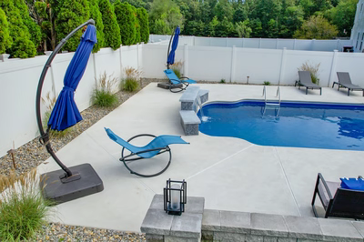 Two-tiered natural stone boulder waterfall cascading into a freeform pool beside modern lounge chairs