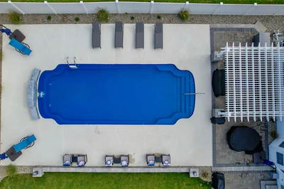 Multi-tiered natural stone boulder waterfall cascading into a blue pool with nearby garden plants