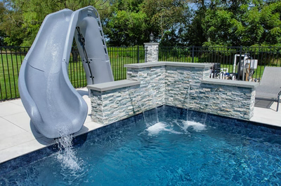 Two-tiered natural stone boulder waterfalls cascading into a pool with lush green landscaping