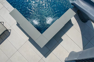 Sleek single-tier geometric stone scuppers flowing into a modern pool with tiled decking