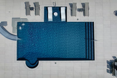 Multi-tiered natural stone boulder waterfall cascading into a rectangular pool with light tiled surroundings