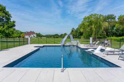 Single tier natural stone boulder waterfall cascading into a rectangular pool beside lush green lawns
