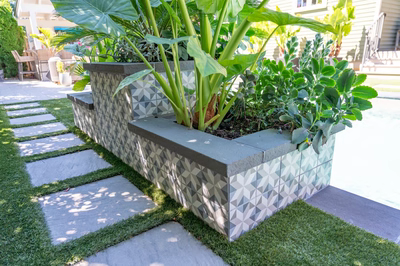 Multi-tiered natural stone boulder waterfall cascading into a pool surrounded by lush tropical plants