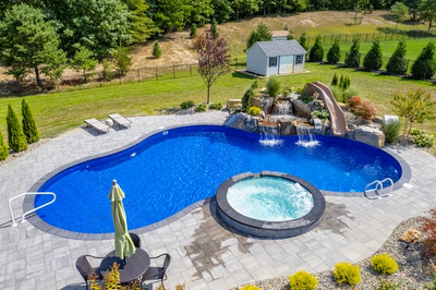 Multi-tiered stone boulder waterfall cascading into a freeform pool surrounded by lush garden plants