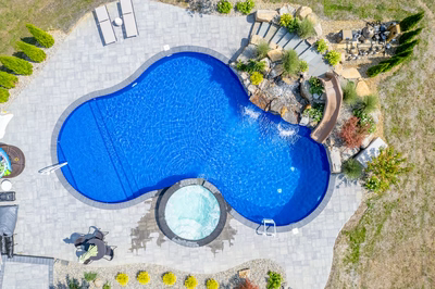 Multi-tiered natural stone boulder waterfall cascading into a freeform pool with lush greenery