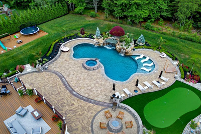 Multi-tiered natural stone boulder waterfall cascading into a freeform pool surrounded by lush greenery