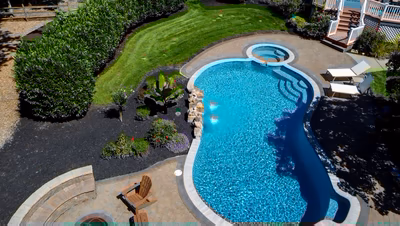 Two-tiered natural stone boulder waterfall cascading into a freeform pool with lush tropical landscaping