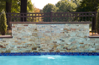 Single-tiered sheer descent natural stone waterfall cascading into a pool with surrounding green trees