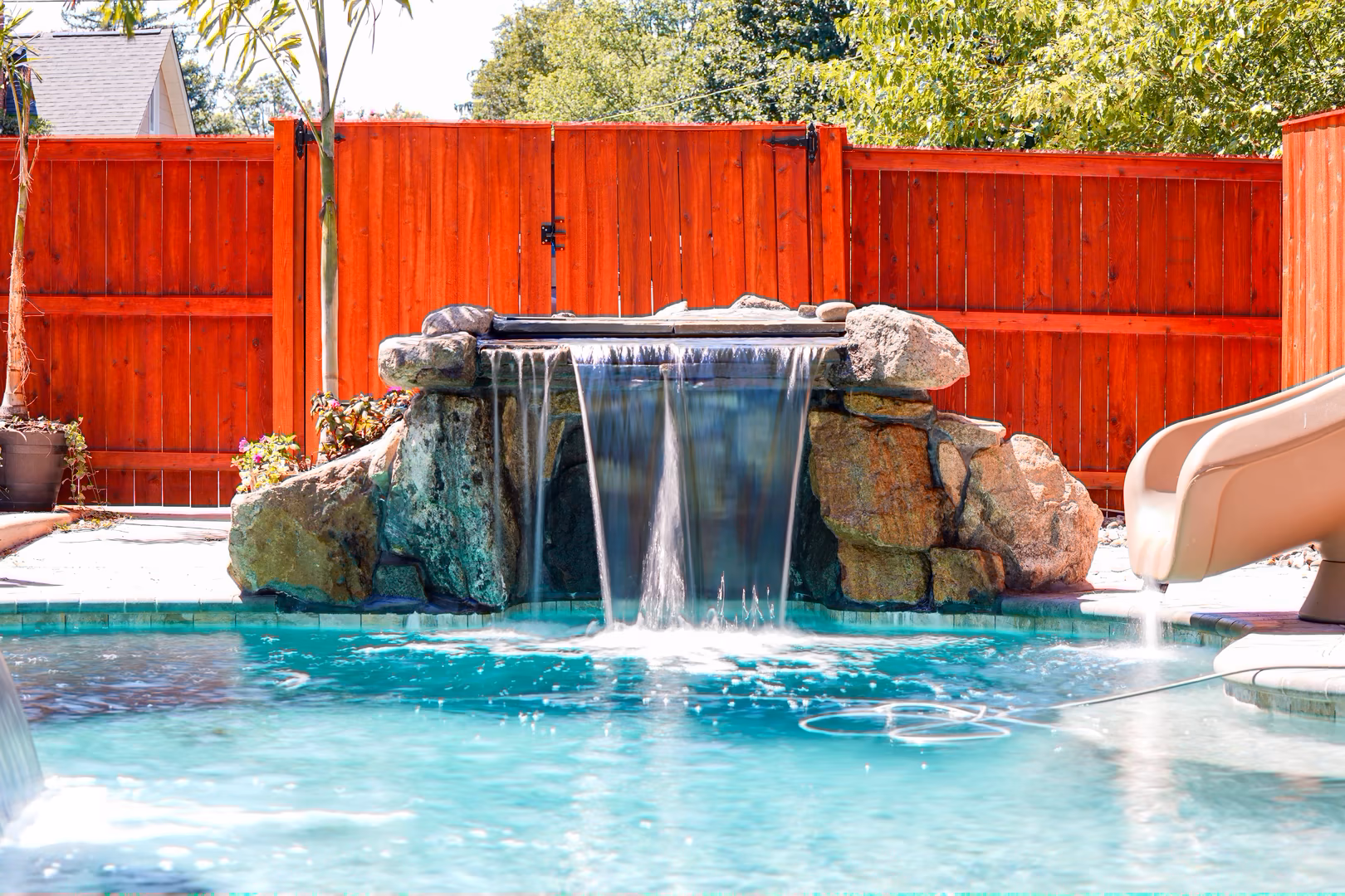 Natural stone boulder waterfall with sheet-like flow cascading into a pool near plants