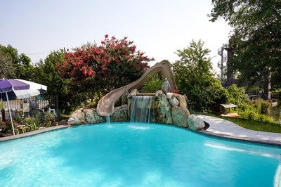 Single-tier natural stone boulder waterfall cascading into a pool surrounded by lush flowering trees