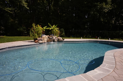 Natural stone boulder waterfall cascading into a freeform pool surrounded by lush tropical greenery