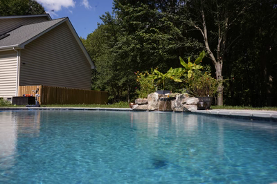 Single-tier natural stone boulder waterfall cascading into a pool surrounded by lush tropical plants